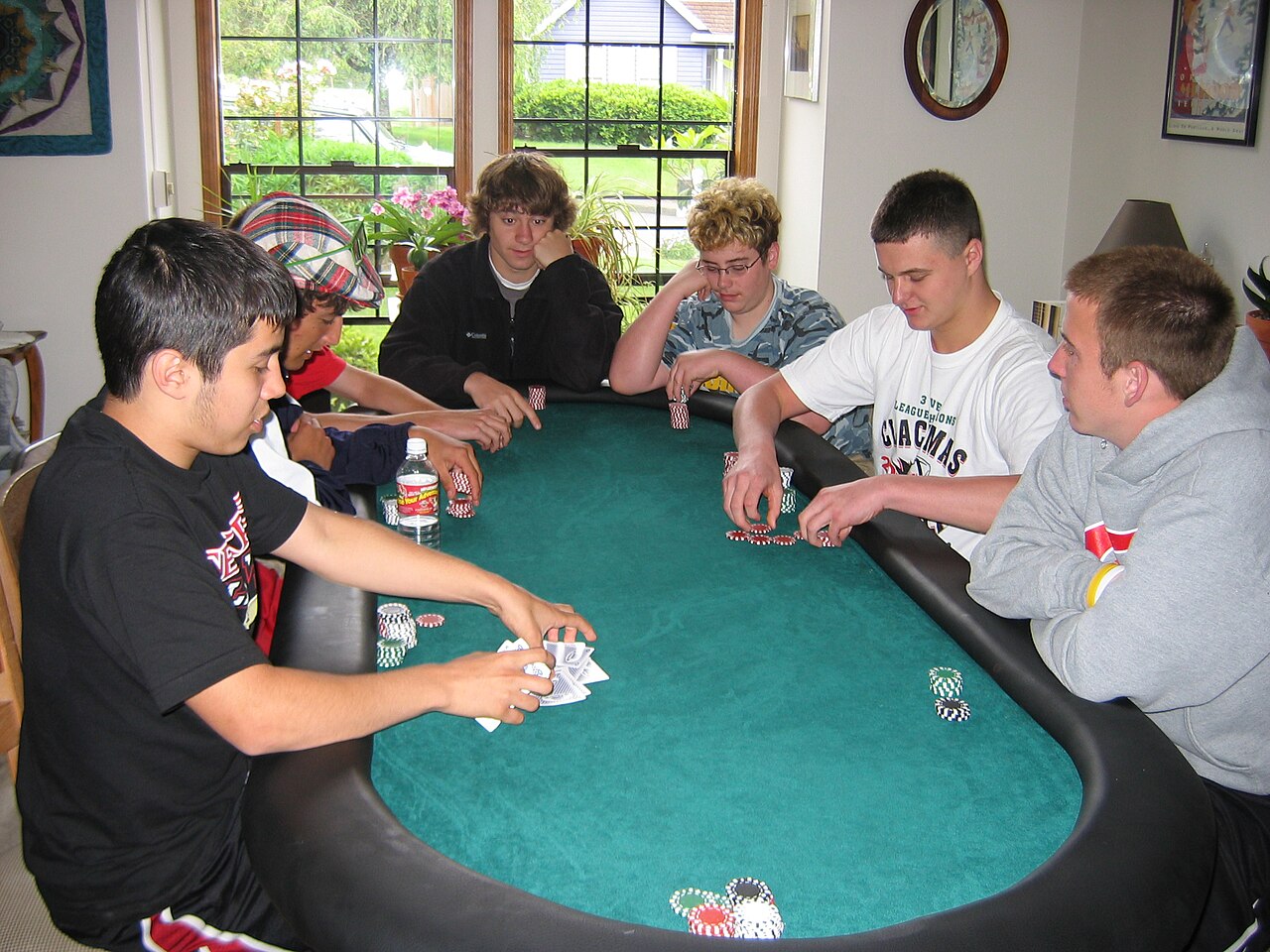 A dealer and players at a poker tournament table with chips and cards in play
